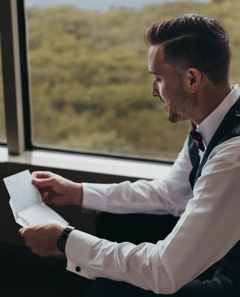 Groom reading his vows by a window before the wedding day ceremony